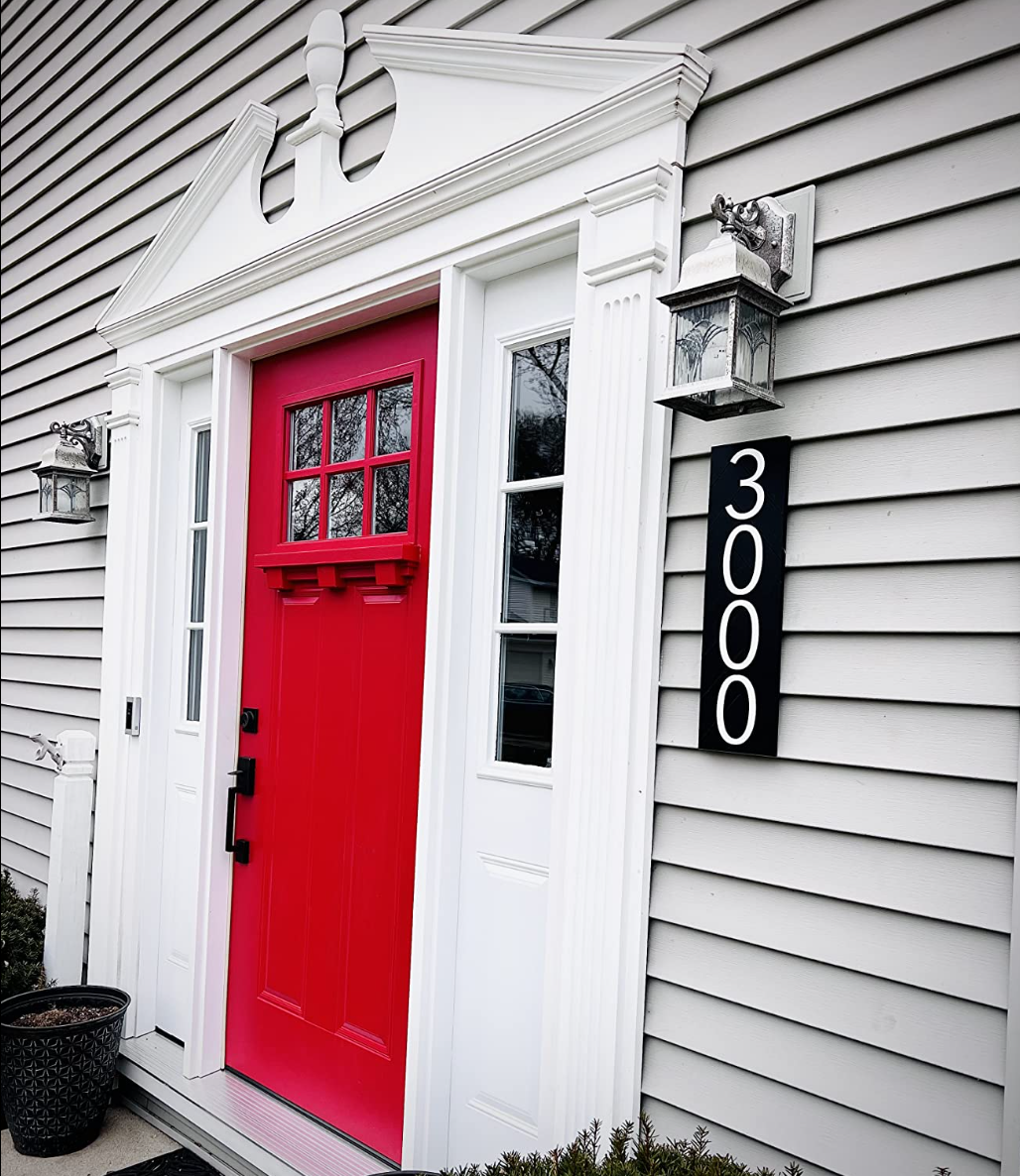 Black vertical modern address sign reading 3000 beside a bright red front door
